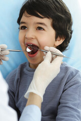 Little arab boy sitting at dental chair with open mouth during oral checking up with dentist doctor. Stomatology concept