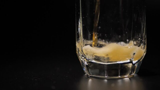 Beer poured into a glass, foam, light, glass spinning, black background