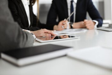 Unknown businessmen and woman sitting, working and discussing questions at meeting in modern office, close-up