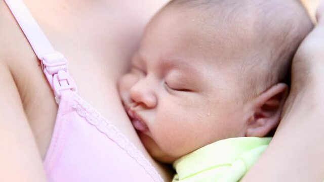 little baby boy sleeping on mom's chest outdoor. mother hugging sleeping baby in her arms and kissing the kid gently.