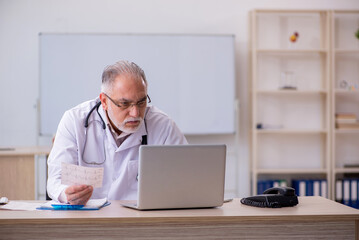 Old male doctor cardiologist working in the clinic