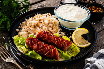 Grilled sausages with basmati rice on wooden table
