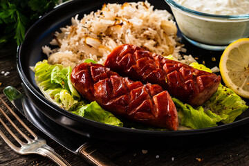 Grilled sausages with basmati rice on wooden table
