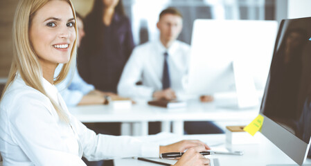 Business woman using computer at workplace in modern office. Secretary or female lawyer smiling and looks happy. Working for pleasure and success