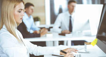 Fototapeta premium Business woman using computer at workplace in modern office. Secretary or female lawyer smiling and looks happy. Working for pleasure and success