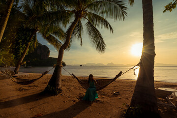 backlight silhouette morning sun beach, coconut tree and woman relex on hammock 