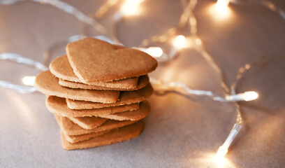 Close up of stacked Gingerbread cookies with christmas lights around. Heart shape cookie. Christmas food. Side view