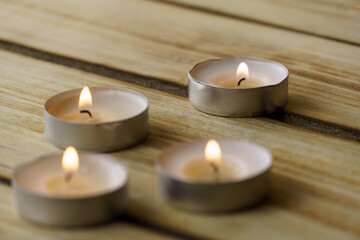 Fototapeta na wymiar Burning candles with on a wood background, shot with shallow depth of field. Spirituality symbol