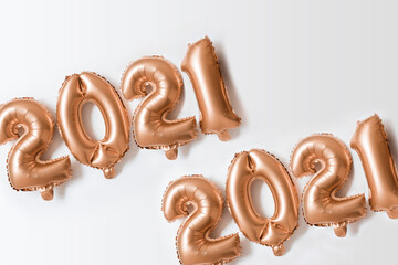 2021 bright gold foil party balloons on white holiday flat lay background. Happy New Year creative concept. Christmas celebration. Minimal composition.