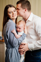 Mom and Dad hold in their arms the infant. 