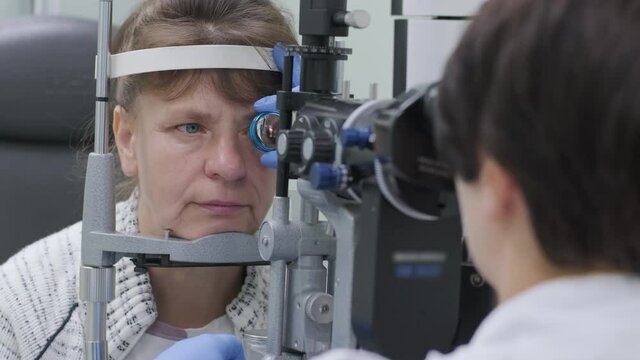 Woman doctor is viewing through ophthalmoscope in eyes of patient in ophthalmologic clinic. Professional inspection of vision