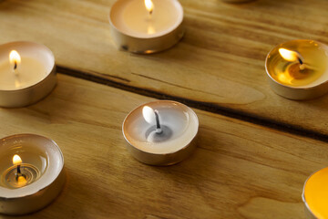 Lots of burning candles on a wooden, shot with shallow depth of field.