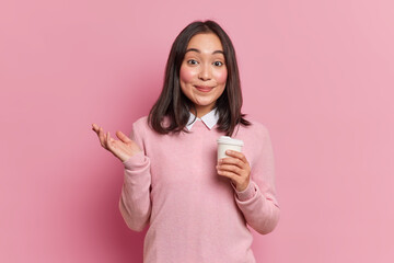 Portrait of lovely Asian woman stands with takeaway coffee raises palm with hesitation gets offer...