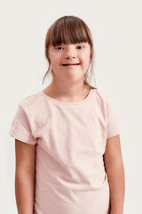 Portrait of disabled girl with Down syndrome smiling at camera while posing isolated over white...