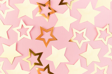 New Year festive abstract background with golden sparkle stars as abstract pattern on pastel pink background.