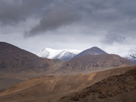 Painterly muted colors of high-altitude mountains on the Pamir Highway near Ak Baital pass in Murghab district, Gorno-Badakshan, Tajikistan on a gloomy overcast day
