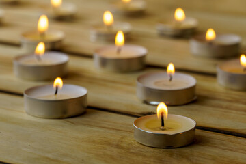 Fototapeta na wymiar Burning candles on a wooden background, shot with shallow depth of field.