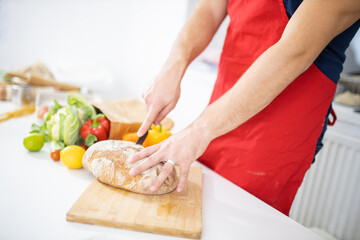 Obraz na płótnie Canvas Male hands slicing bread on a cutting board