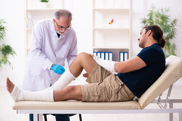 Fototapeta premium Young injured man visiting old doctor traumatologist