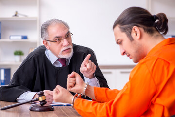Old male judge meeting with young captive in courthouse
