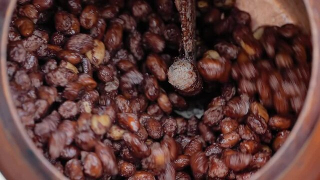 Professional nut roaster machine for mixing, roasting and glazing peanuts: close up, slow motion. Production, manufacturing, preparation, technology and street food concept