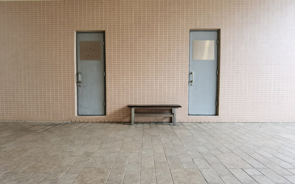 two doors on a brick wall with a wood bench between. copy space in front floor.