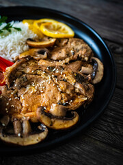 Fried pork steaks with lemon, basmati rice and steamed pak choi cabbage served on wooden table
