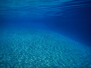 deep blue clear sea water with reflection on sandy bottom