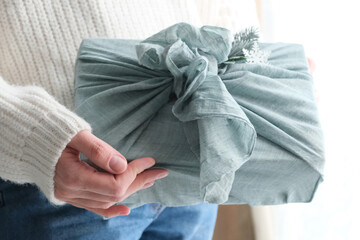 wrapping gifts in fabric for Christmas in furoshiki style. Eco friendly concept. DIY.