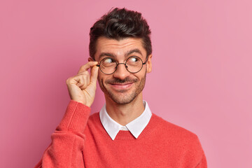 Headshot of handsome European man with bristle looks aside and smiles pleasantly has thoughtful...