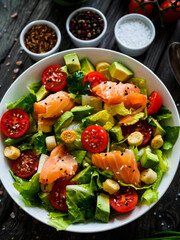 Salmon salad - smoked salmon with avocado and mix of  vegetables on wooden table