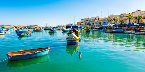 Colorful painted wood boats with the typical protective eyes on a sunny day  in Marsaxlokk, Malta.
