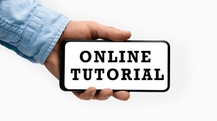 Closeup of a male hand holding Smartphone with text Online Tutorial on display