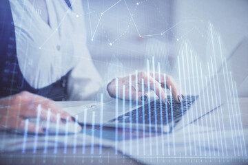 Double exposure of businesswoman hands typing on computer and forex graph hologram drawing. Financial analysis concept.