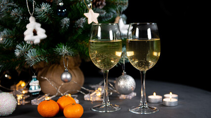 new year's still life, 2 glasses of champagne tangerines on the table on the background of the Christmas tree