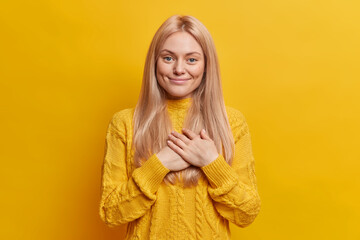 Charming lovely blonde woman keeps hands pressed together appreciates your help being touched by...