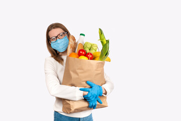 Young woman in disposable gloves and face mask holding Box with food ingredients