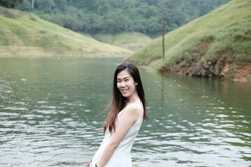 Asian woman wear white dress is smiling near the river in forest. Freedom life in nature Concept.