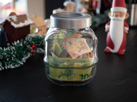Saving money, donation concept. Glass jar with euros and christmas decoration in background.