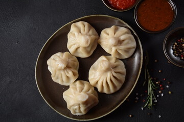 Obraz na płótnie Canvas Georgian dumplings Khinkali with meat and red pepper, Traditional National Georgian cuisine. Khinkali with local sauces - tkemali, satsebeli, adzhika.