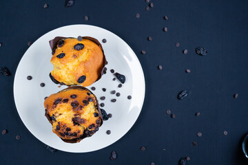 Chocolate, raisin chips and chocolate raisin muffin on a white plate. black background. 