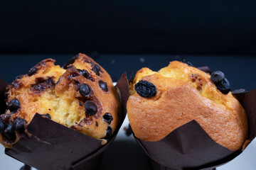Chocolate, raisin chips and chocolate raisin muffin on a white plate. black background. 