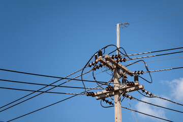 An electricity power distributor concrete pole with orderly cable lines. In clearly blue sky...