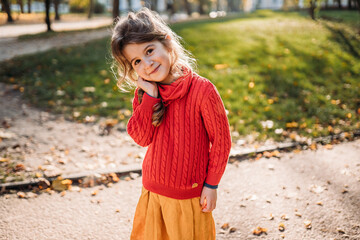 lovely little girl in the park in autumn smiling