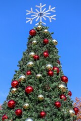 Christmas background bright large red and gold balls on green branches of an artificial Christmas tree with a snowflake on the top