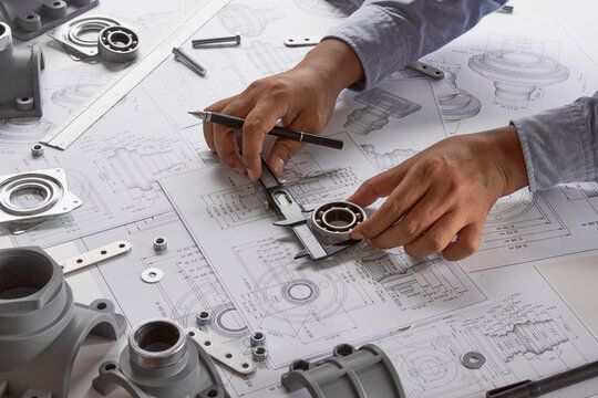 Engineer technician designing drawings mechanical parts engineering Engine.manufacturing factory Industry Industrial work project blueprints measuring bearings caliper tools