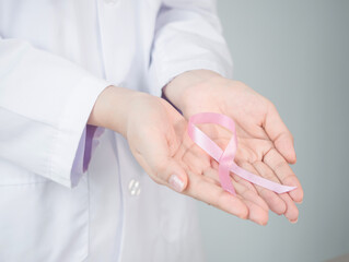 Pink bow in female doctor’s hand with with background copy-space. charity for cancer desease...
