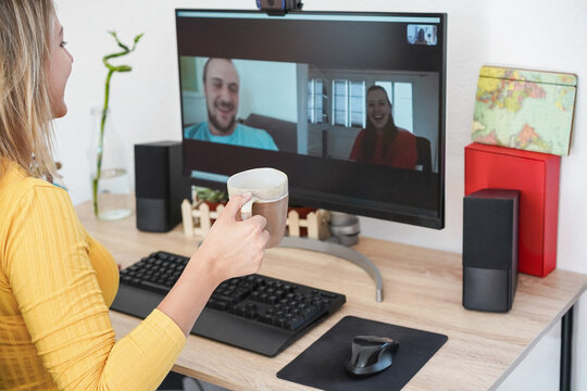Young woman having online video call using computer app with friends while drinking coffee at home - Technology, coronavirus lockdown and restrictions concept - Focus on hand cup