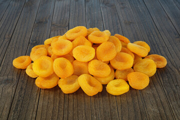 A handful of dried apricots on a wooden backing.