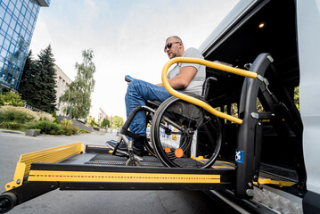A man in a wheelchair on a lift of a vehicle for people with disabilities